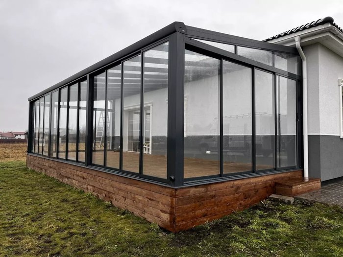 Jardin d’hiver installé sur une terrasse en bois, ouvert sur le jardin