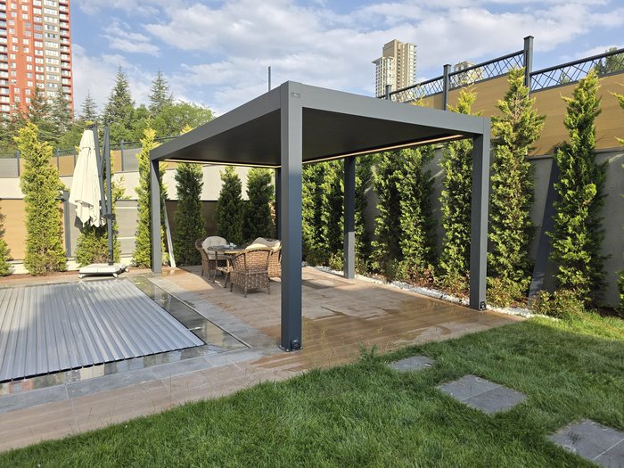 Pergola bioclimatique en aluminium anthracite au bord d’une piscine